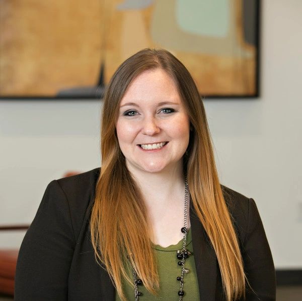 Smiling woman with long blonde hair in business casual attire.