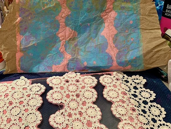 Crocheted lace pieces and colorful paper artwork.