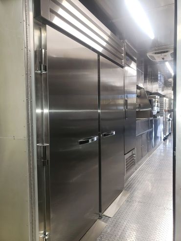 Interior of a clean, stainless steel commercial kitchen or food truck.