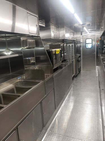 Inside view of a clean, modern stainless steel commercial kitchen in a food truck.