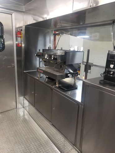Stainless steel commercial espresso machine setup inside a mobile unit.