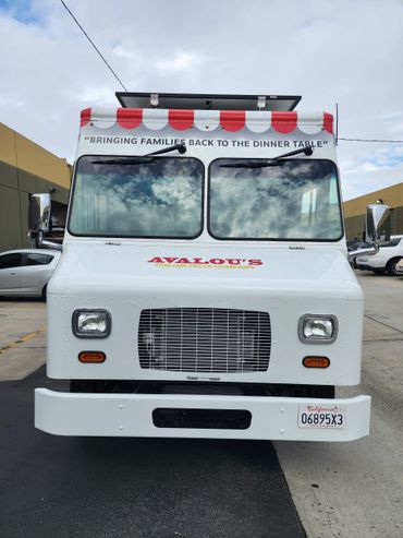 Front view of Avalou's Italian Pizza Company food truck with a red and white striped awning.