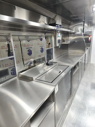 Sleek, empty stainless steel commercial kitchen interior with modern equipment.