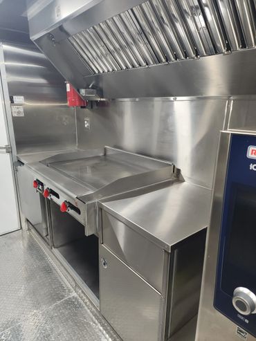Clean, stainless steel commercial kitchen with stove and ventilation hood.