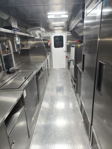 Interior of a clean, stainless steel commercial kitchen with appliances and storage.