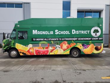 Green Magnolia School District truck with vibrant fruit graphics and an inspiring message.