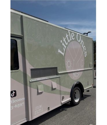 Side view of a Little Ones food truck with pastel green and pink design.