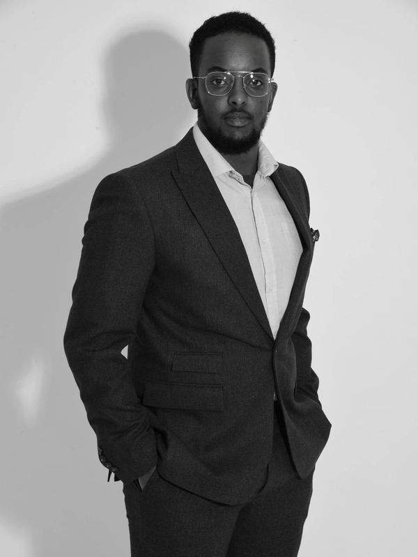 Confident man in a suit posing against a plain background.