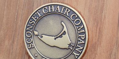 Brass logo of the Sconset Chair Company, embedded into the backrest of a solid teak Sconset Chair