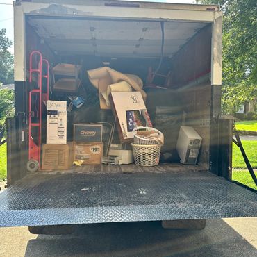 Moving truck loaded with boxes, furniture, and household items on a sunny day.
