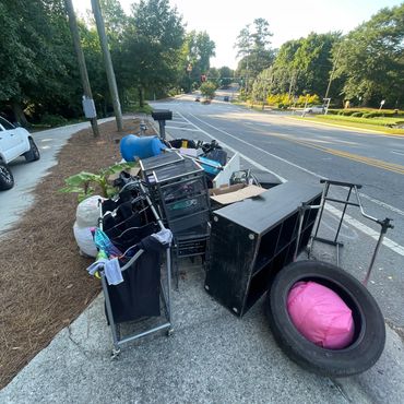 Discarded household items and furniture piled on a street corner.