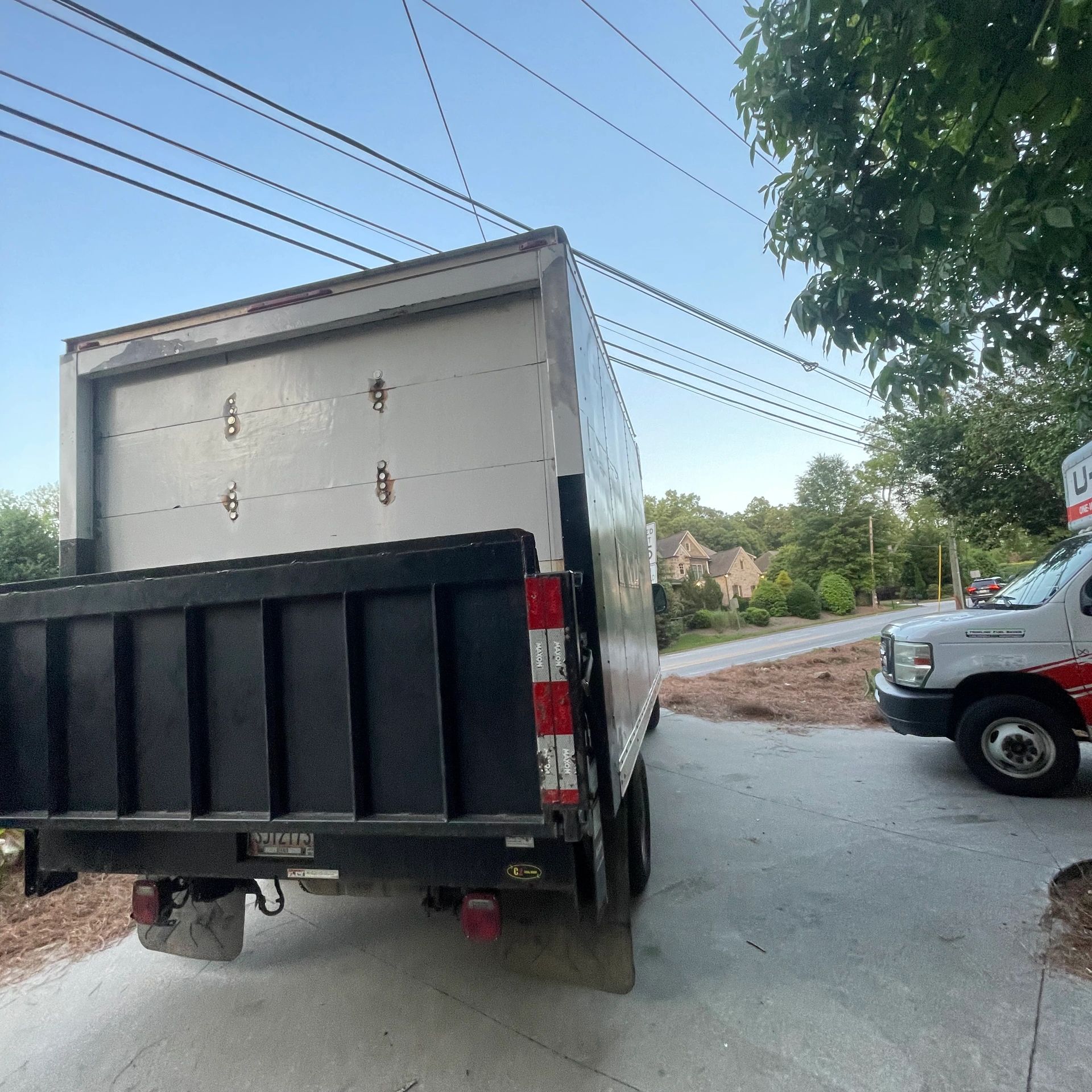 Two trucks parked near a residential driveway under clear skies.