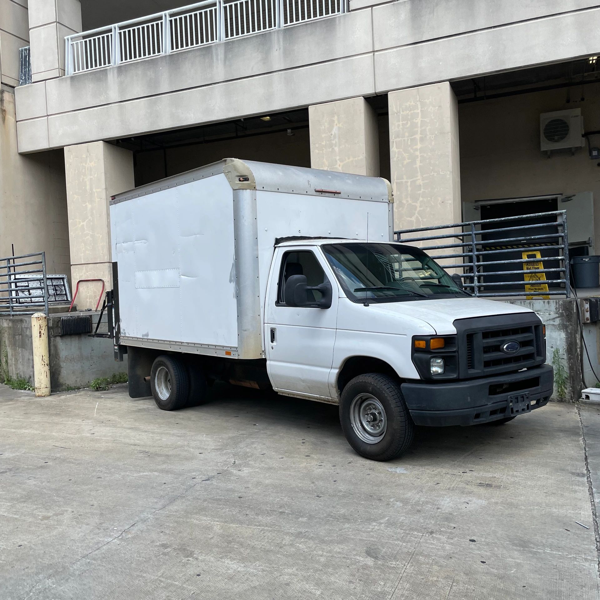 White box truck parked by a concrete loading dock in an urban area.