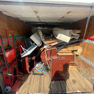 A moving truck loaded with disassembled furniture and two red hand trucks.