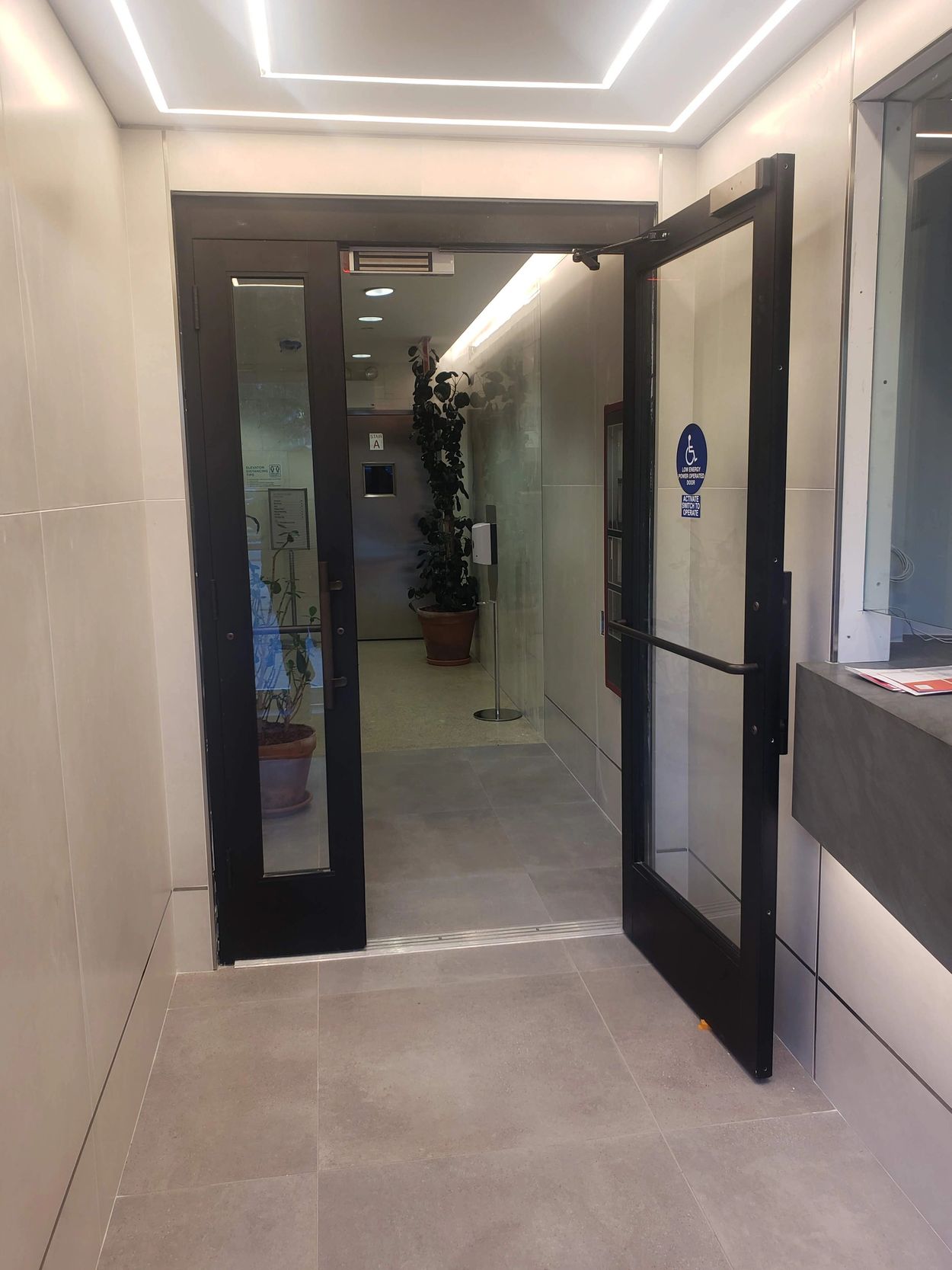 Modern glass door entrance with accessibility sign in a clean hallway.