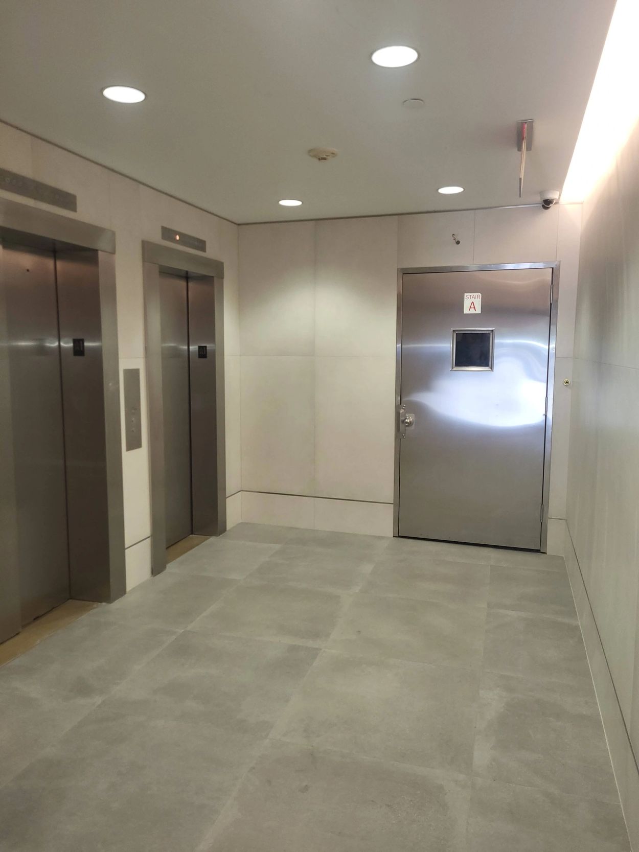 Modern elevator lobby with two elevators and a stair door.