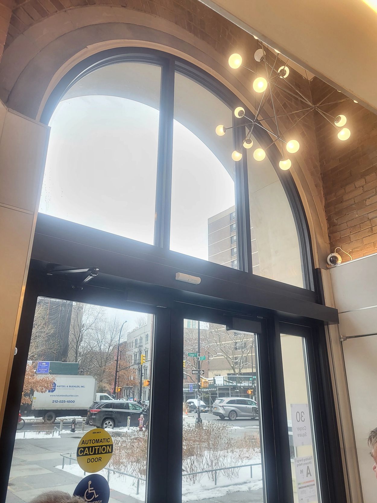 Large arched glass door with a modern chandelier inside a building.
