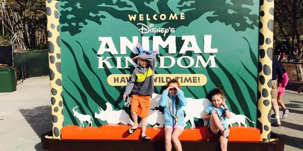 Kids sitting in front of the Disney's Animal Kingdom Park Welcome Sign