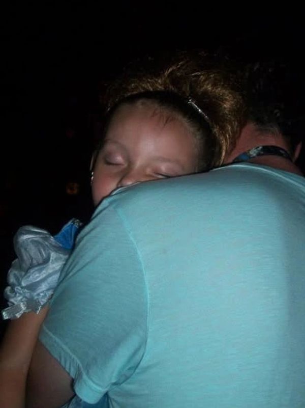 Olivia sleeping in dad's arms dressed as Cinderella after a long day at Magic Kingdom