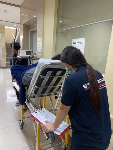 Medical staff pushing a patient on a stretcher in a hospital corridor.
