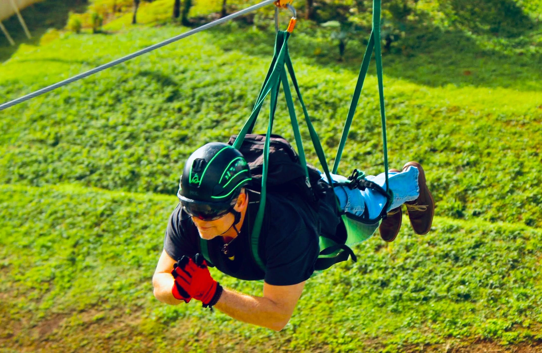 Person enjoying an outdoor ziplining adventure over green terrain.