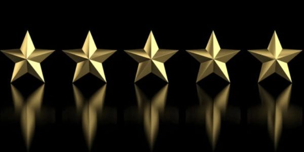 Five golden stars in a row on a black reflective flat surface
