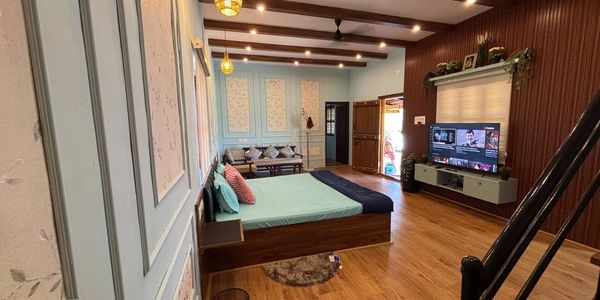 Modern bedroom with wooden flooring, blue walls, and a TV setup.