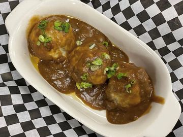 Smoked meatballs with melted Monterey cheese,  gravy and topped with green onions.