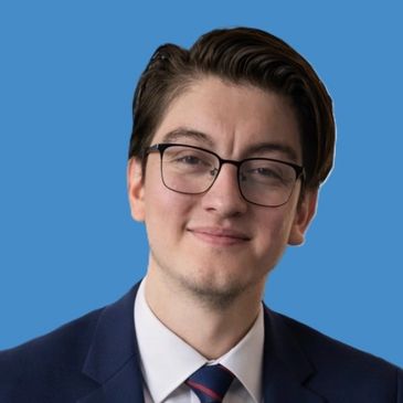 Young man in glasses and suit against blue background.
