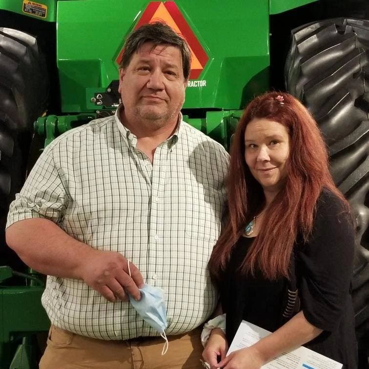 male and female standing in front of a tractor