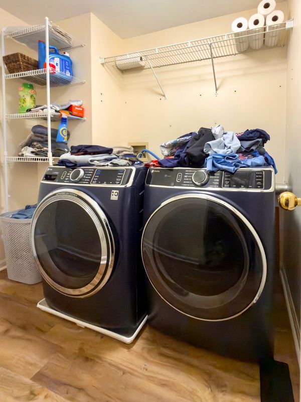 Laundry room with blank walls and wire shelves before KBC Studio remodel