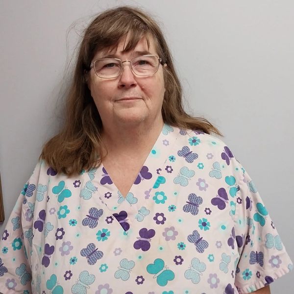 Woman wearing butterfly and flower patterned scrub top.