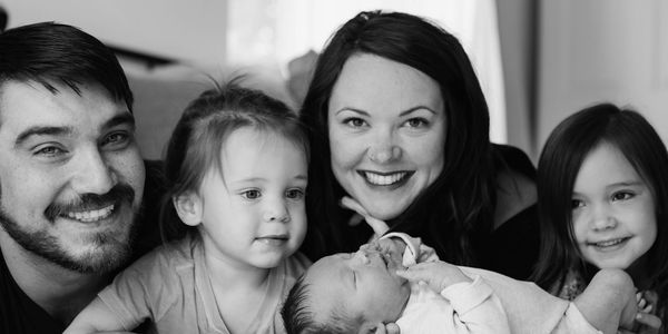 Happy family smiling together with a newborn baby in black and white.