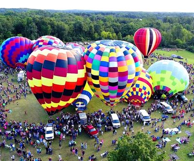 Colorful hot air balloons preparing for flight at a crowded festival.