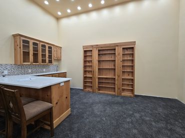 Spacious kitchen with wooden cabinets and a large empty bookshelf.