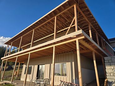 Wooden framework of a two-story house under construction on a sunny day.