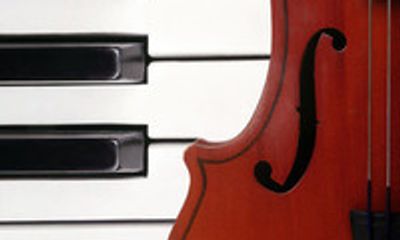 Close-up of piano keys and violin body.
