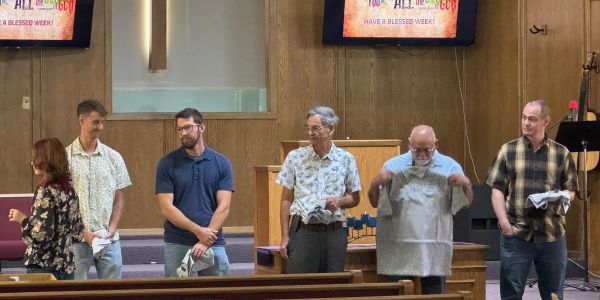 People standing in a church holding folded shirts.