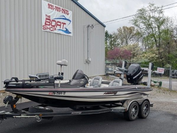 Bass fishing boat on trailer outside a boat shop.