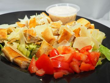 A delicious Caesar Salad with tomatoes,  croutons and parmesan cheese.