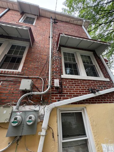 Red brick building exterior with windows, utility meters, and electrical wires.