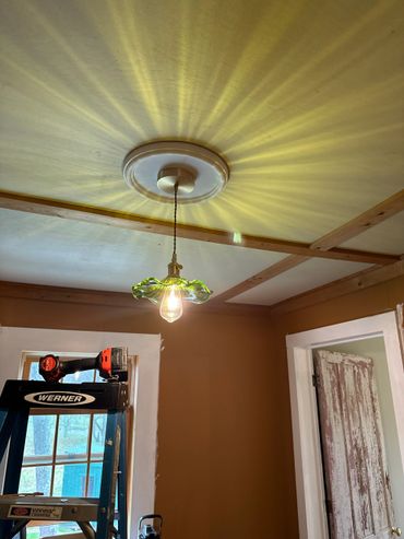 Light fixture casting radiant patterns on a ceiling in a room under renovation.