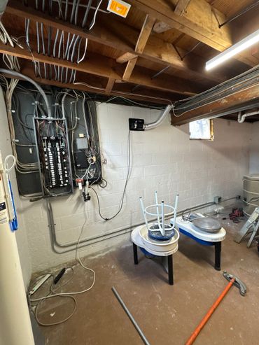 A basement workspace with pottery wheels and exposed electrical panels.