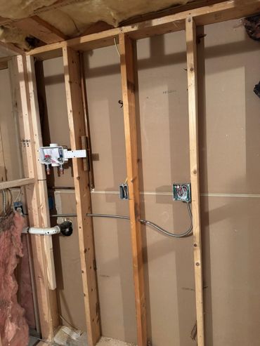 Exposed wall framing with plumbing and electrical wiring installed.