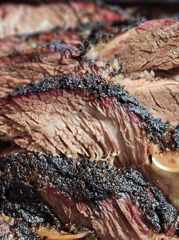 Close-up of sliced smoked brisket with a dark, flavorful crust.