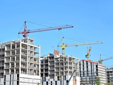 Multiple cranes at a construction site with unfinished buildings.