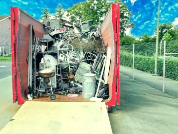 Dumpster full of old metal and household items.