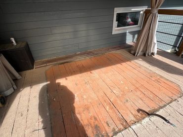 Worn wooden deck with a shadow and an exposed cable.