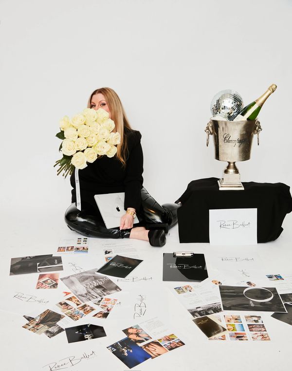 Woman surrounded by branded materials and a bouquet of white roses.
