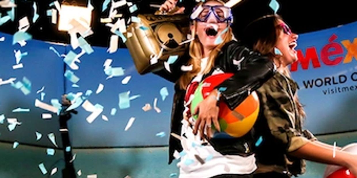 Two women celebrate with confetti, holding a beach ball and wearing goggles.